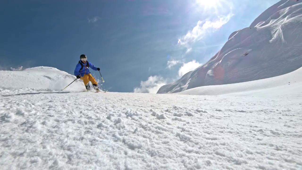 SLO MO男性滑雪者骑下雪道在一个阳光明媚的山视频素材