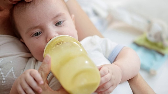 小男孩在母亲的怀里用奶瓶喂奶视频下载