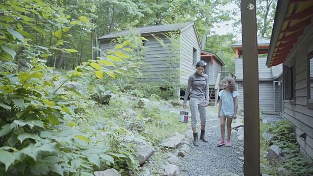 一个女人和一个女孩在小屋附近散步聊天视频素材