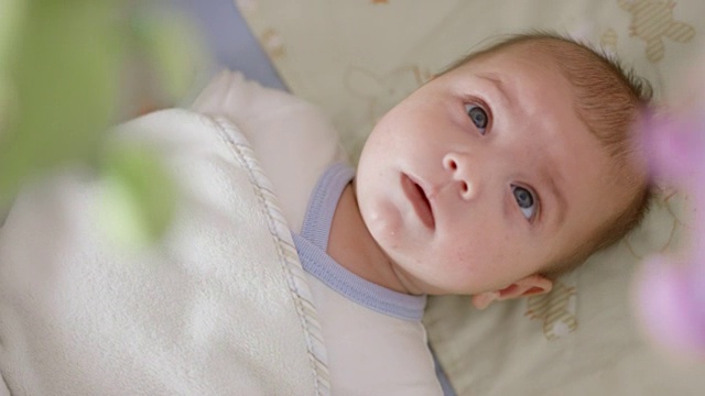 男婴躺在床上观察婴儿的移动视频下载