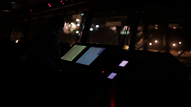 一名船员在集装箱船桥上操作控制面板的夜景。视频素材
