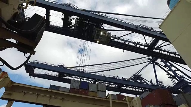 在费利克斯托港，起重机从一艘集装箱船的甲板上吊起一个集装箱的低角度拍摄。视频素材