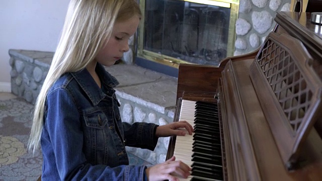 年轻的女孩在家里弹钢琴。视频下载