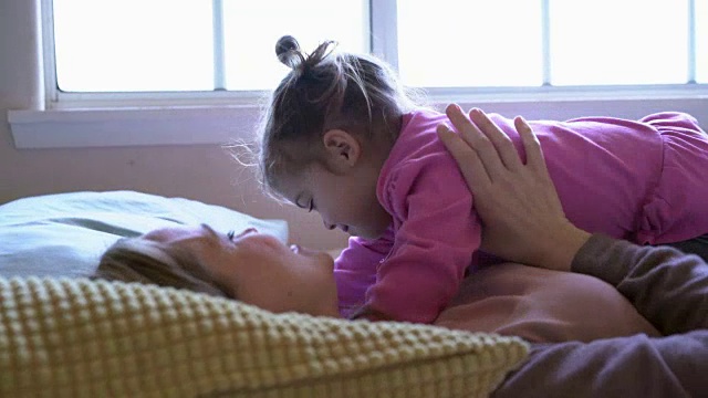 CU母亲和女婴一起在床上玩视频素材