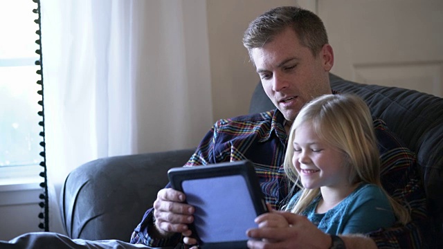 父亲和女儿一起在平板电脑上玩视频下载