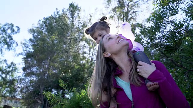 母亲背着她的女儿，她的肩膀上戴着仙女的翅膀视频下载
