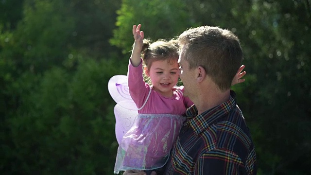 父亲和戴着蝴蝶翅膀的小女儿说话视频下载