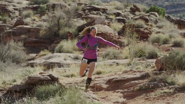 宽跟踪镜头夫妇trail跑步在沙漠/摩押，犹他州，美国视频下载