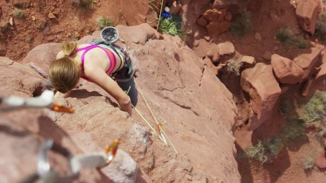 宽高角度拍摄的妇女攀登岩层/费舍尔塔，犹他州，美国视频下载