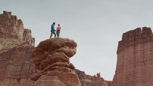 宽低角度平移拍摄夫妇站在岩层/费舍尔塔，犹他州，美国视频素材