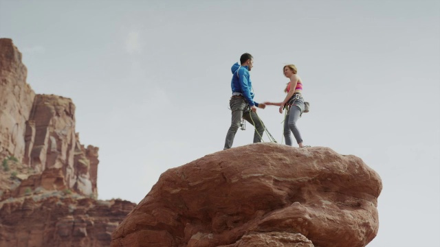 宽低角度慢镜头夫妇庆祝岩石形成/费舍尔塔，美国犹他州视频素材