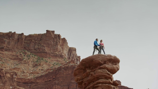 宽低角度平移拍摄夫妇站在岩层/费舍尔塔，犹他州，美国视频素材