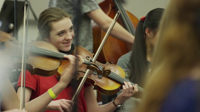 少女在管弦乐队演奏小提琴的中镜头/美国犹他州的美国叉视频素材