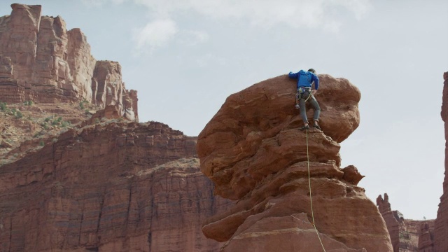 宽低角度平移拍摄的人攀登岩石/费舍尔塔，犹他州，美国视频素材