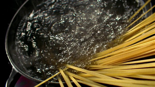 慢镜头高角度靠近锅的沸水和未煮的面条丝落入视频素材