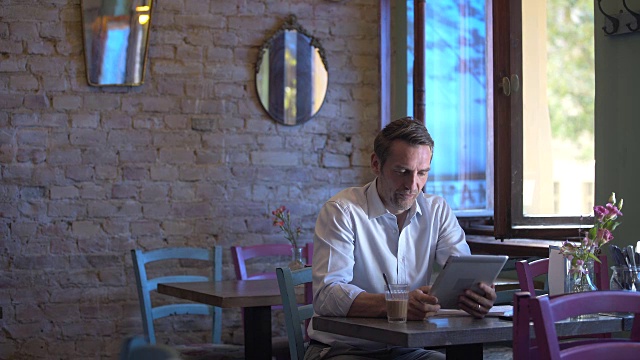 一个商人在café上使用他的平板电脑视频素材