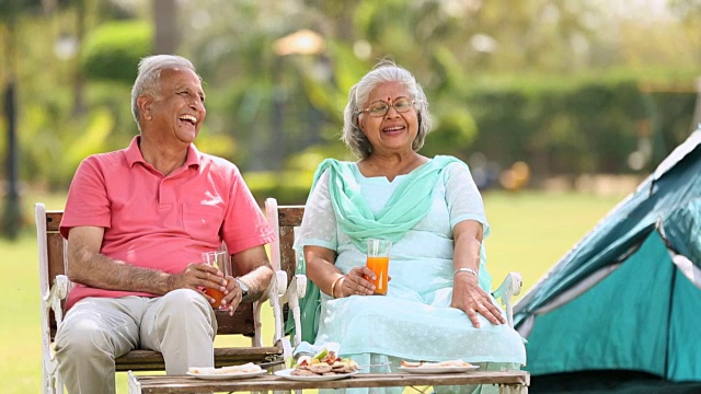 印度德里，一对老年夫妇在公园里喝果汁视频下载