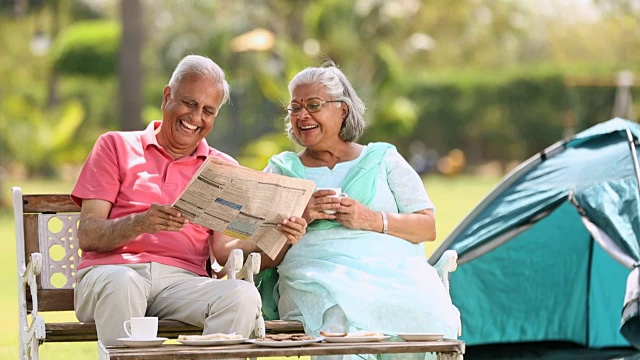 印度德里，一对老年夫妇在公园里看报纸视频下载