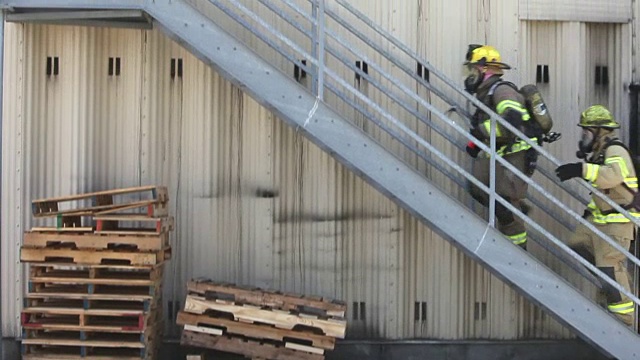 消防队员穿着装备爬楼梯到仓库门口视频素材