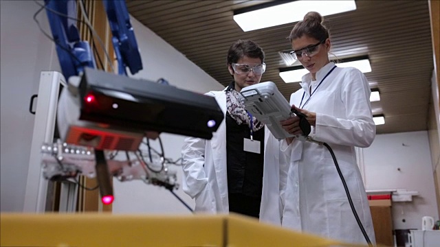 在实验室里使用机械臂工作的女性工程师视频下载