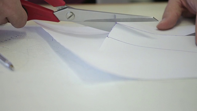 一个裁缝裁剪服装图案的近景。视频下载