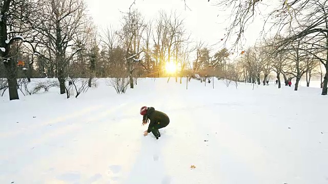 日落时分，女人在公园里玩雪。视频素材