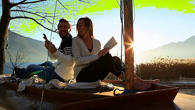 年轻夫妇在自然中放松，阅读书籍和平板电脑视频下载