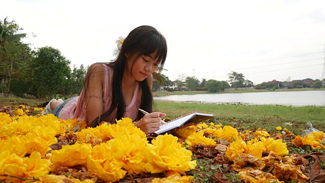 亚洲女孩躺在草地上看书视频下载
