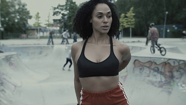 在德国柏林的城市设置的滑板公园前，女运动员伸展/热身。视频下载