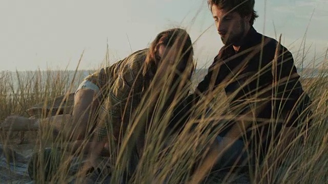 年轻情侣在法国南部的沙滩上野餐，在沙丘上倒酒。视频下载