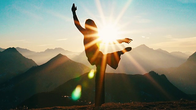 日出时，一个年轻女子在山顶做瑜伽视频素材