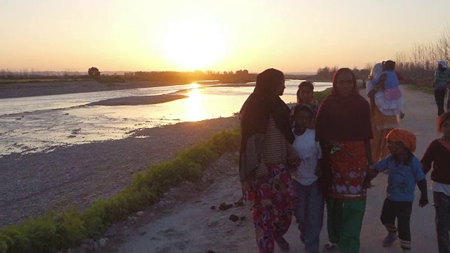 一家人在日落中漫步在乡村的河边。视频素材