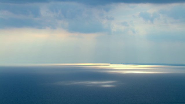 阳光穿过稀薄的云层，照射在墨西哥湾平静的海面上。视频下载