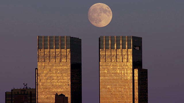 在纽约，月亮从两座相同的摩天大楼上升起，反射出落日的余晖视频素材