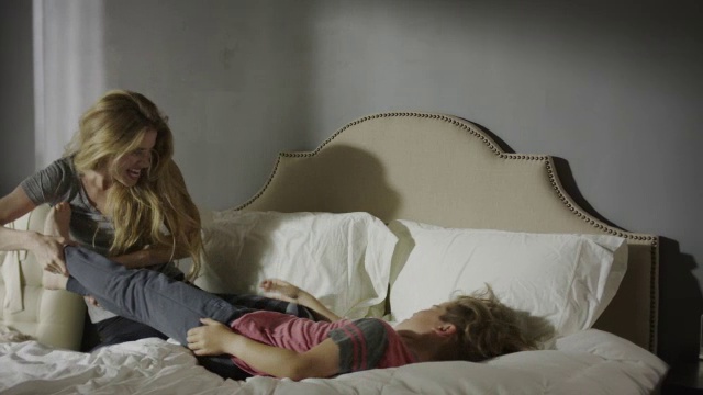 中等平移拍摄的母亲在床上挠儿子/雪松山，犹他州，美国视频素材
