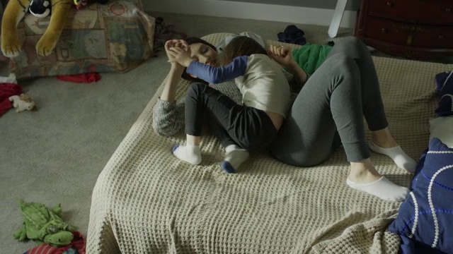 中等高角度平移拍摄母亲在床上挠儿子/雪松山，犹他州，美国视频素材