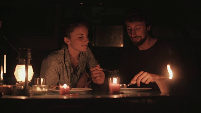 在法国南部的露营地，一对年轻情侣在大众汽车前的烛光下吃晚餐。视频素材