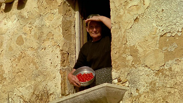 低角度MS资深妇女在房子的窗户上遮阳眼睛+拿着碗西红柿/ Custonaci，西西里视频下载