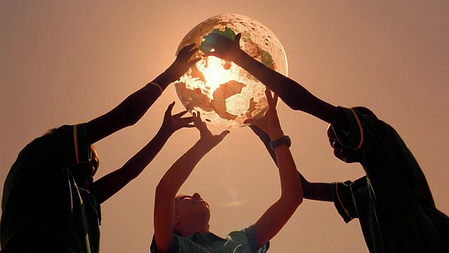两名黑人少年和白人少女在肯尼亚户外举着地球灯，背景是太阳视频下载