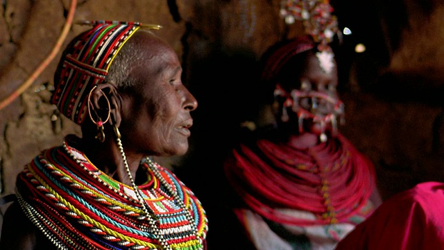 MS机架聚焦高级马赛部落妇女转身+看着相机与年轻的马赛妇女在背景/肯尼亚视频下载