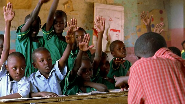 MS年轻的黑人学生坐在课桌前+兴奋地举起手/肯尼亚视频素材