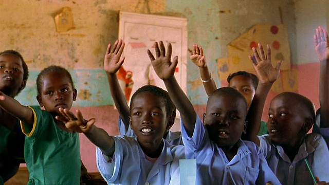 年轻的黑人学生坐在课桌前+兴奋地举起手/肯尼亚视频素材