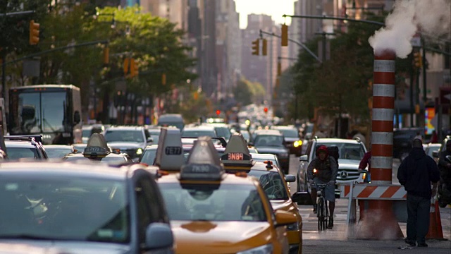 出租车和公共汽车在纽约市繁忙的街道上行驶。蒸汽从橙色圆锥体中升起。视频素材