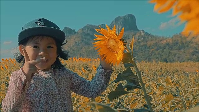 亚洲小女孩在向日葵地里快乐地微笑视频素材