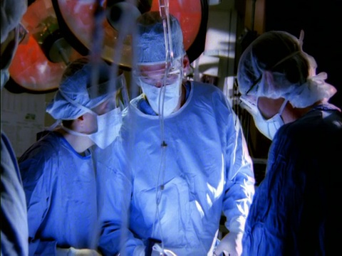 中镜头女性和男性外科医生在手术室观看主外科医生做手术视频素材
