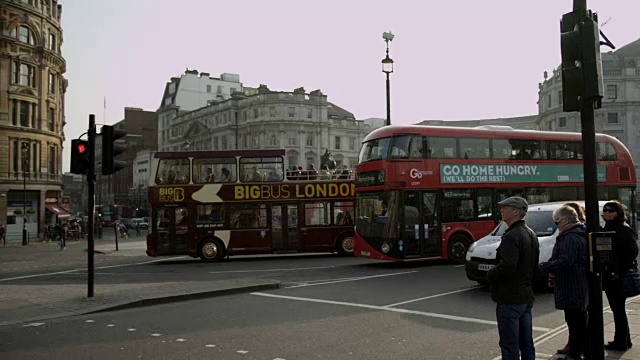 伦敦双层巴士在特拉法加广场，晴朗晴朗的一天。行人走过视频素材
