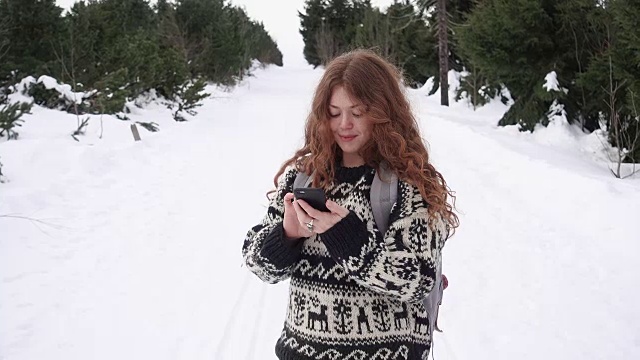 一名女子在冬季徒步旅行时发短信视频素材