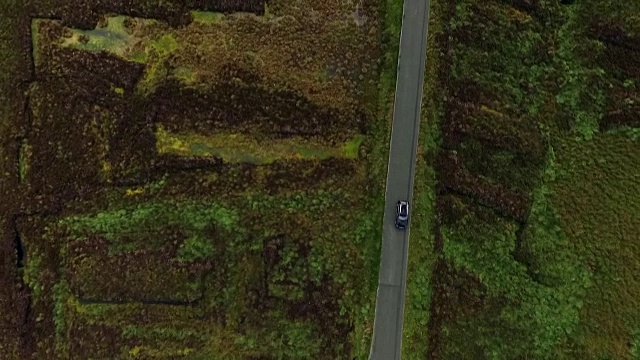 航拍镜头显示一辆奥迪Q3汽车在爱尔兰威克洛县威克洛山国家公园的荒原上行驶。视频下载