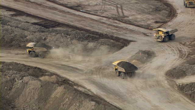 在加拿大麦克默里堡(Fort McMurray)，一辆自卸卡车装载着油砂穿过一座矿场。视频素材