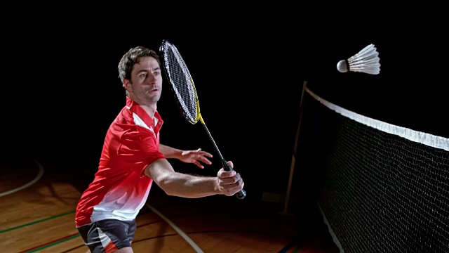 SLO MO男子羽毛球运动员穿着红色的衬衫打羽毛球视频素材